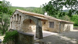 A stone building with a tiled roof, arched windows, and a small porch area. - house / villa - Saint-PrivatHouse with garden (Saint-Privat)