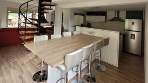 A modern kitchen with a wooden dining table, white chairs, and a black spiral staircase. - house / villa - Saint-PrivatHouse with garden (Saint-Privat)