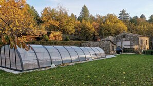 A greenhouse structure in a grassy area with a stone building in the background. - house / villa - Saint-PrivatHouse with garden (Saint-Privat)