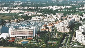 Zona turística costera con varios edificios de gran altura, un puerto deportivo y una playa de arena.