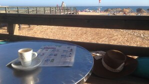 Vista de la playa desde una mesa con un menú, una taza de café y un sombrero.