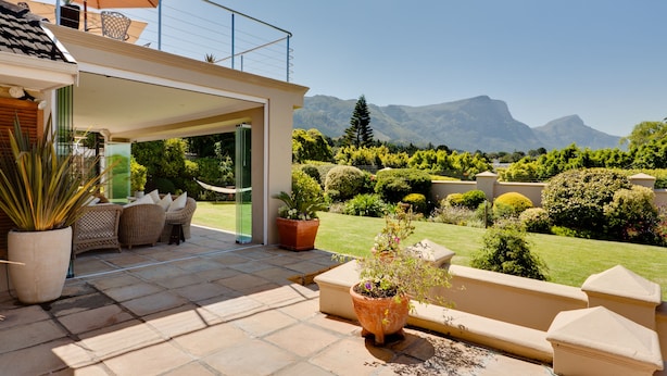 Un patio con mobiliario exterior, plantas en macetas y vistas a montañas.