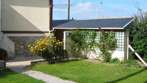 A residential house with a small garden, a gravel pathway, and a fence with climbing plants.