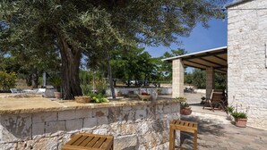 An outdoor seating area with stone walls, wooden chairs, and potted plants. - Villa in Monopoli for 12 guests in six bedroom (Bari)