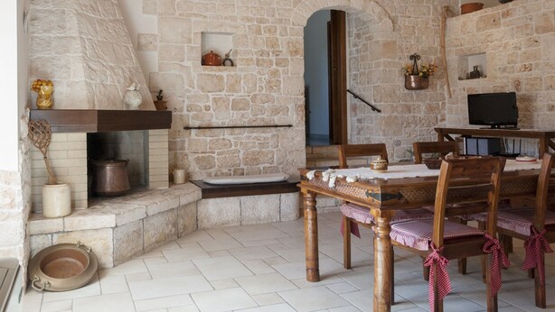 A rustic stone interior with a fireplace, wooden dining table, and chairs. - Villa in Monopoli for 12 guests in six bedroom (Bari)