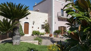 A building with a stone facade, a wooden door, and potted plants in the courtyard. - Villa in Monopoli for 12 guests in six bedroom (Bari)