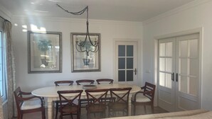 A dining area with a round table, six wooden chairs, two framed pictures, a chandelier, and a door with glass panels. - 3 bedrooms, 3 bathrooms, private heated pool, garden area and golf course views (San Roque)