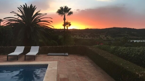 A swimming pool with two lounge chairs, palm trees, and a sunset view. - 3 bedrooms, 3 bathrooms, private heated pool, garden area and golf course views (San Roque)