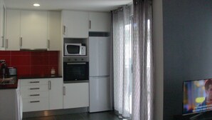 A compact kitchen with white cabinets, a microwave, and a refrigerator. - excellent for families (Portimão)