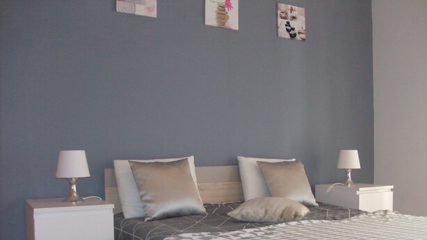 A bedroom with a bed, two nightstands, and a wall with three pictures. - excellent for families (Portimão)