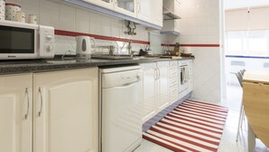 Una cocina moderna con armarios blancos, microondas y un tapete a rayas rojas.