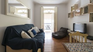 Una sala de estar con sofá, mesa de centro, televisor y un espejo grande.
