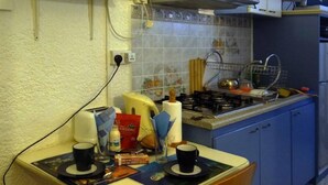A small kitchen with a table, chairs, a gas stove, and various kitchen items.