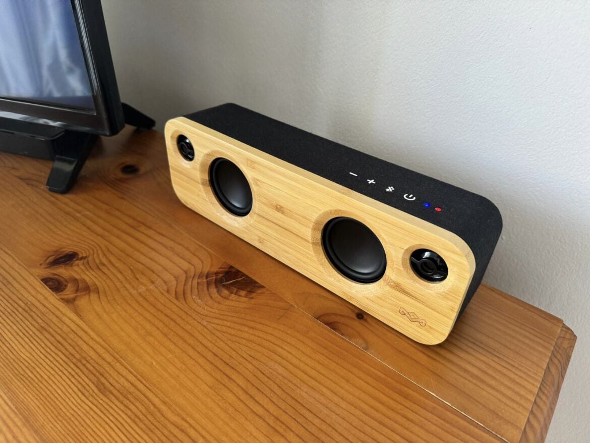 A wooden speaker with two black circular speakers and a control panel on a wooden table.