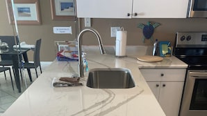 Een keuken met een wit marmeren aanrechtblad, een roestvrijstalen spoelbak en een inbouwoven.