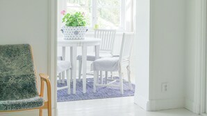 A bright, white room with a wooden floor, a white table with chairs, and a window with a view of greenery. - Unique Countryside Villa From The 17th Century, Close To Stockholm (Drottningholm)