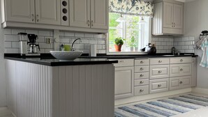 A kitchen with a central island, white cabinetry, a window with a view, and a striped rug. - Unique Countryside Villa From The 17th Century, Close To Stockholm (Drottningholm)