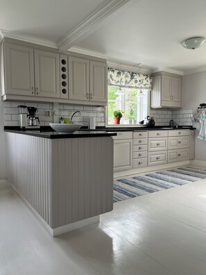 A kitchen with a central island, white cabinetry, a window with a view, and a striped rug. - Unique Countryside Villa From The 17th Century, Close To Stockholm (Drottningholm)