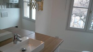 A modern bathroom with a wooden vanity, a sink, a washing machine, and a toilet. - Beautiful and quiet apartment in the heart of the Cité des Papes (Avignon)