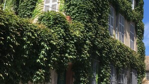 A building with a stone facade partially covered in green ivy. - Beautiful and quiet apartment in the heart of the Cité des Papes (Avignon)