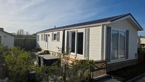 A mobile home with a patio, sliding doors, and a fenced backyard.