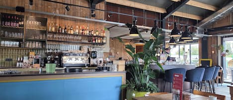 Eine Bar mit Theke, Espressomaschinen und Regalen voller Flaschen und Gläsern.