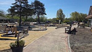 A paved pathway leading to a seating area with benches, surrounded by gravel and potted plants.