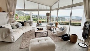 A spacious living room with a large window offering a scenic view of a mountainous landscape. - Breathtaking sea view in exclusive design villa!  (Tourrettes-Sur-Loup)