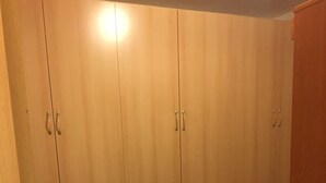 A room with wooden flooring, a wooden wardrobe with multiple drawers, and a small wooden table. - WONDER FLAT ORTIGIA: elegant flat (Siracusa)