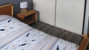 Et hotelværelse med en seng, et natbord, en lampe og en skydedør.