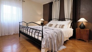 Een slaapkamer met een bed, twee nachtkastjes, een raam en gordijnen.