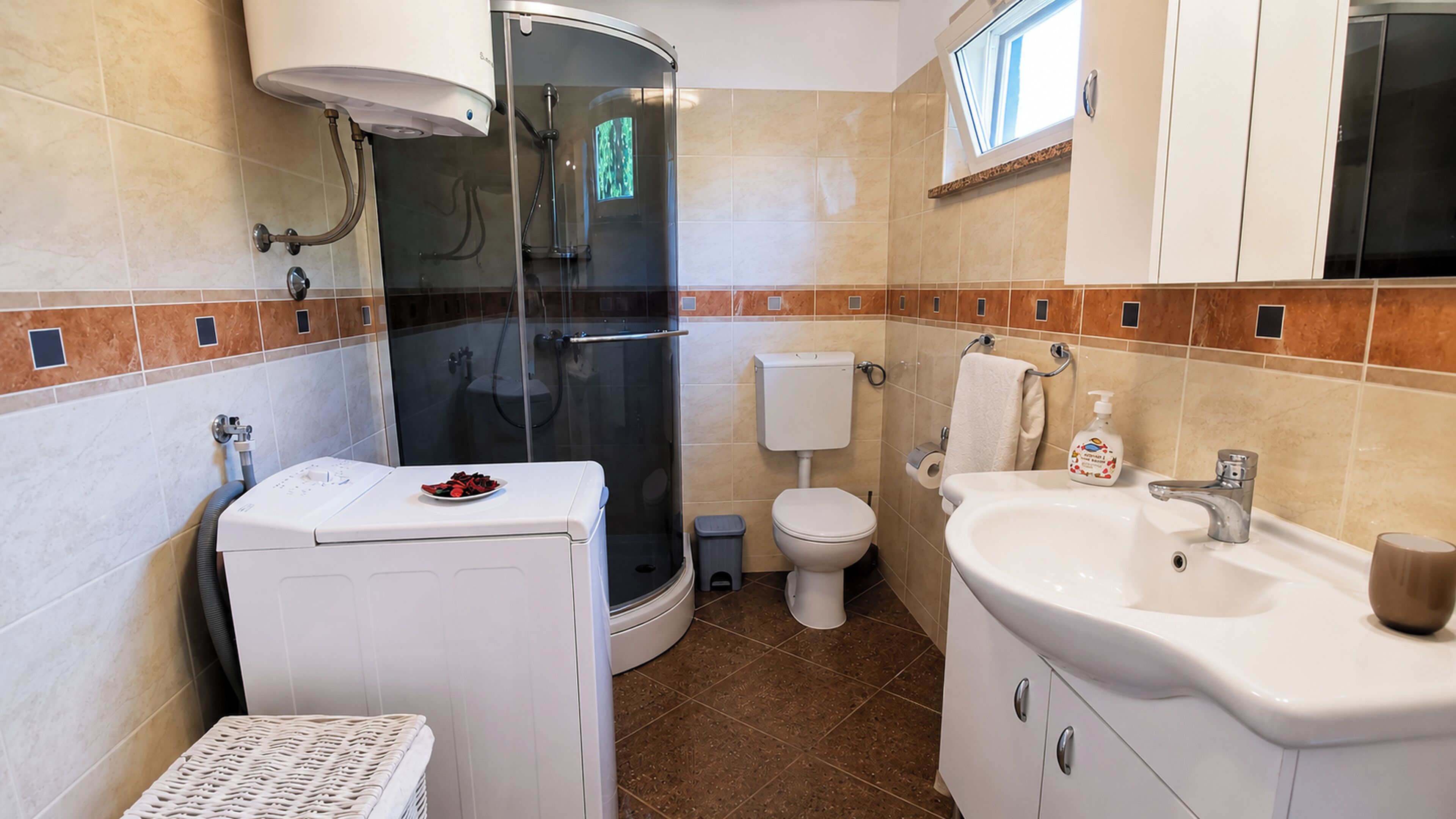 Un baño con ducha, inodoro, lavabo y una lavadora pequeña.
