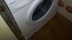 Une machine à laver à chargement frontal, dotée d’un panneau de commande et d’une plaque décorative sur le dessus.