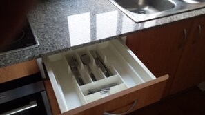 Un cajón de cocina con utensilios.