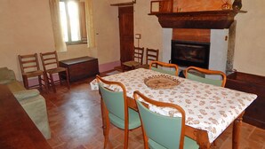 Une salle à manger avec une table en bois, des chaises et une cheminée.