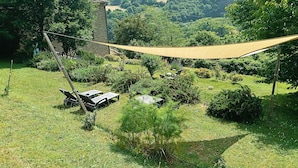 Un jardin agrémenté d’un hamac, d’une structure en pierre et offrant une vue sur la verdure environnante.