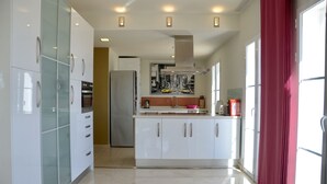 A modern kitchen with white cabinets, a central island, and a red curtain. - Spacious modern villa - fabulous sea views, free WIFI, beach & golf (Golf Bahía)