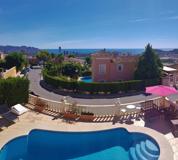 A pool area with a view of a cityscape and the sea.
