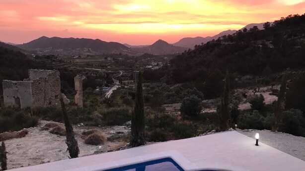 Une piscine offrant une vue sur un paysage montagneux et sur des ruines en arrière-plan.