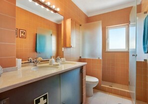 A modern bathroom with two sinks, a toilet, and a glass-enclosed shower.