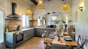 A modern kitchen with a central island, pendant lights, and a dining area with a table set for two.