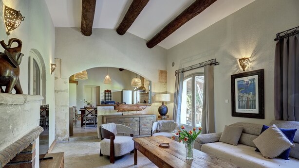 A spacious living area with a sofa, a wooden table, and a kitchen in the background.