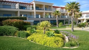 Un hotel de varios pisos con balcones, abundante vegetación y palmeras.