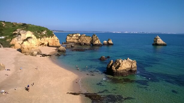 Una playa costera con aguas cristalinas y formaciones rocosas.