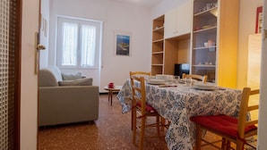 Un coin repas avec une table dressée pour quatre personnes, un canapé et une bibliothèque.