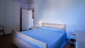 Une chambre à coucher avec un lit, une table de chevet, une lampe et une armoire.