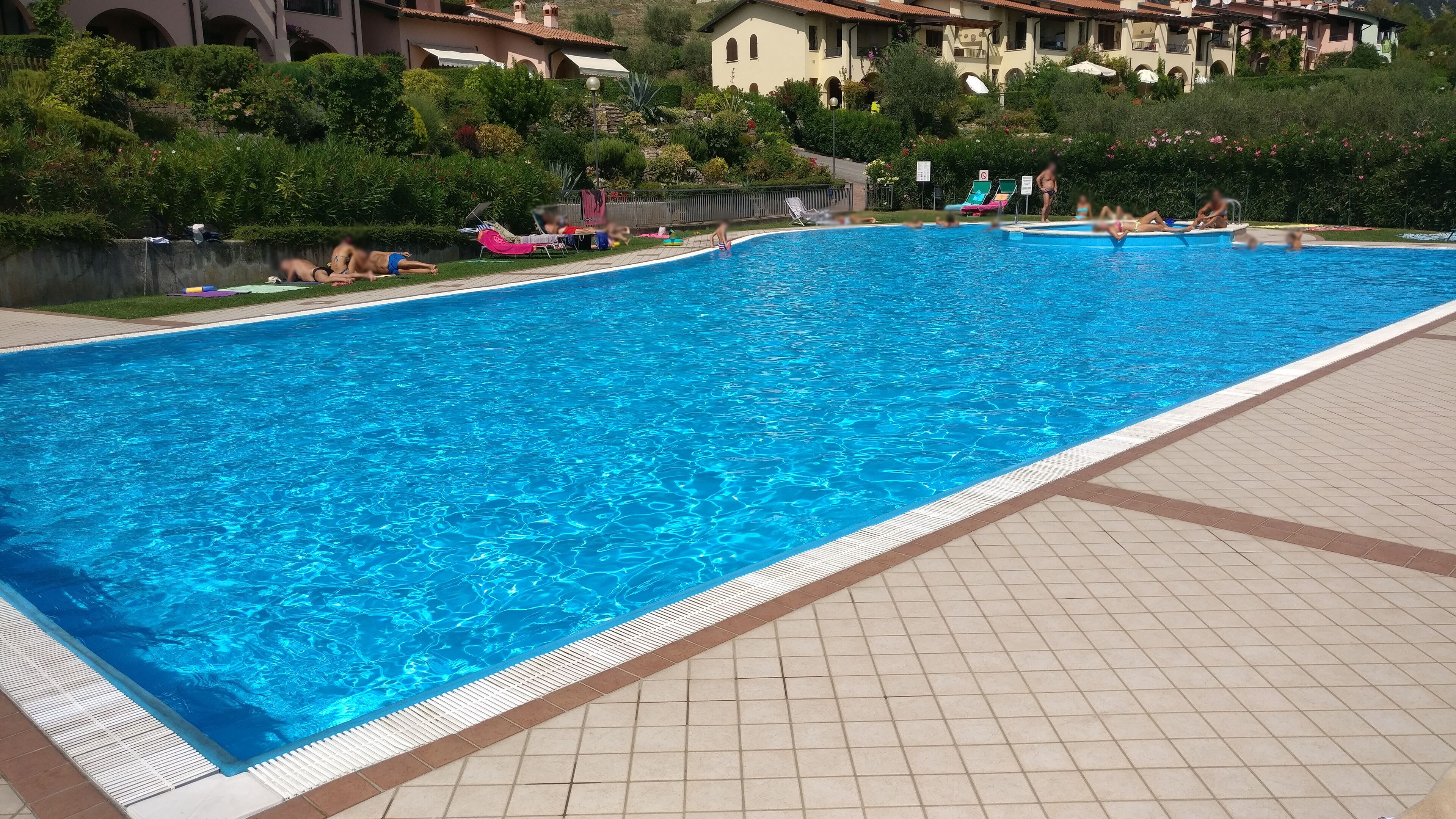 A large swimming pool with tiled deck and lounge chairs.
