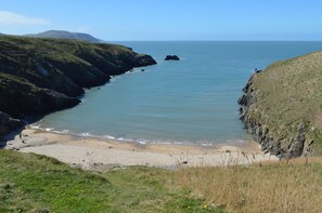 Un paysage côtier avec une plage, des falaises rocheuses et un ciel dégagé.