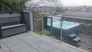 Ein Balkon mit Whirlpool, einer Sitzbank und Blick auf die Stadt.