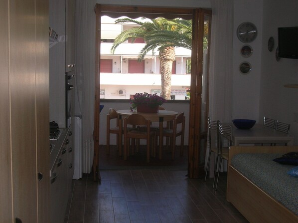 Una habitación con zona de comedor, cama y vista a un edificio.
